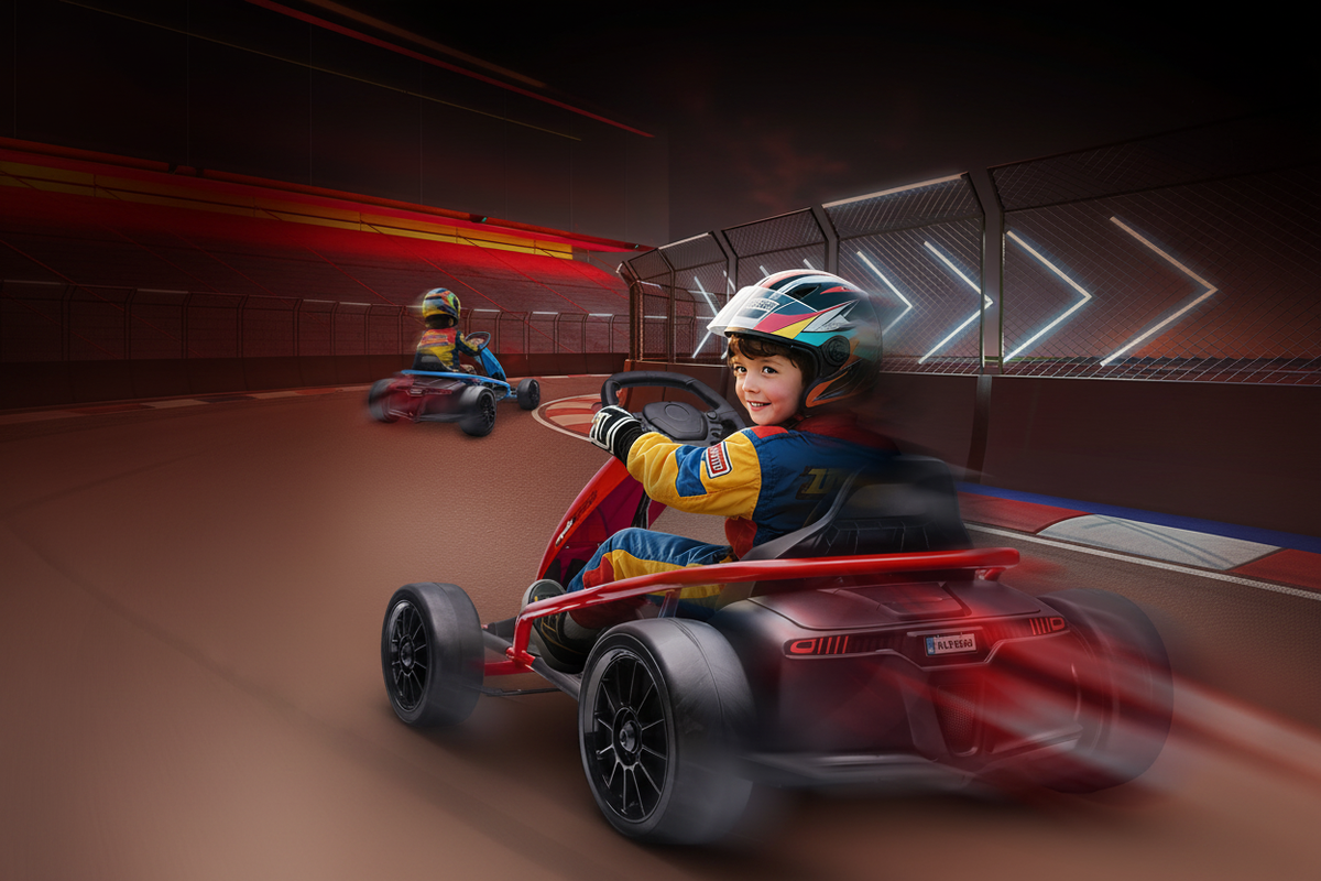 Child in racing gear drifting red 24V electric go-kart on indoor track